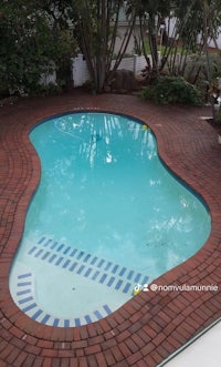 a swimming pool in a backyard with brick pavers