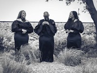 a black and white photo of a group of women dressed in black